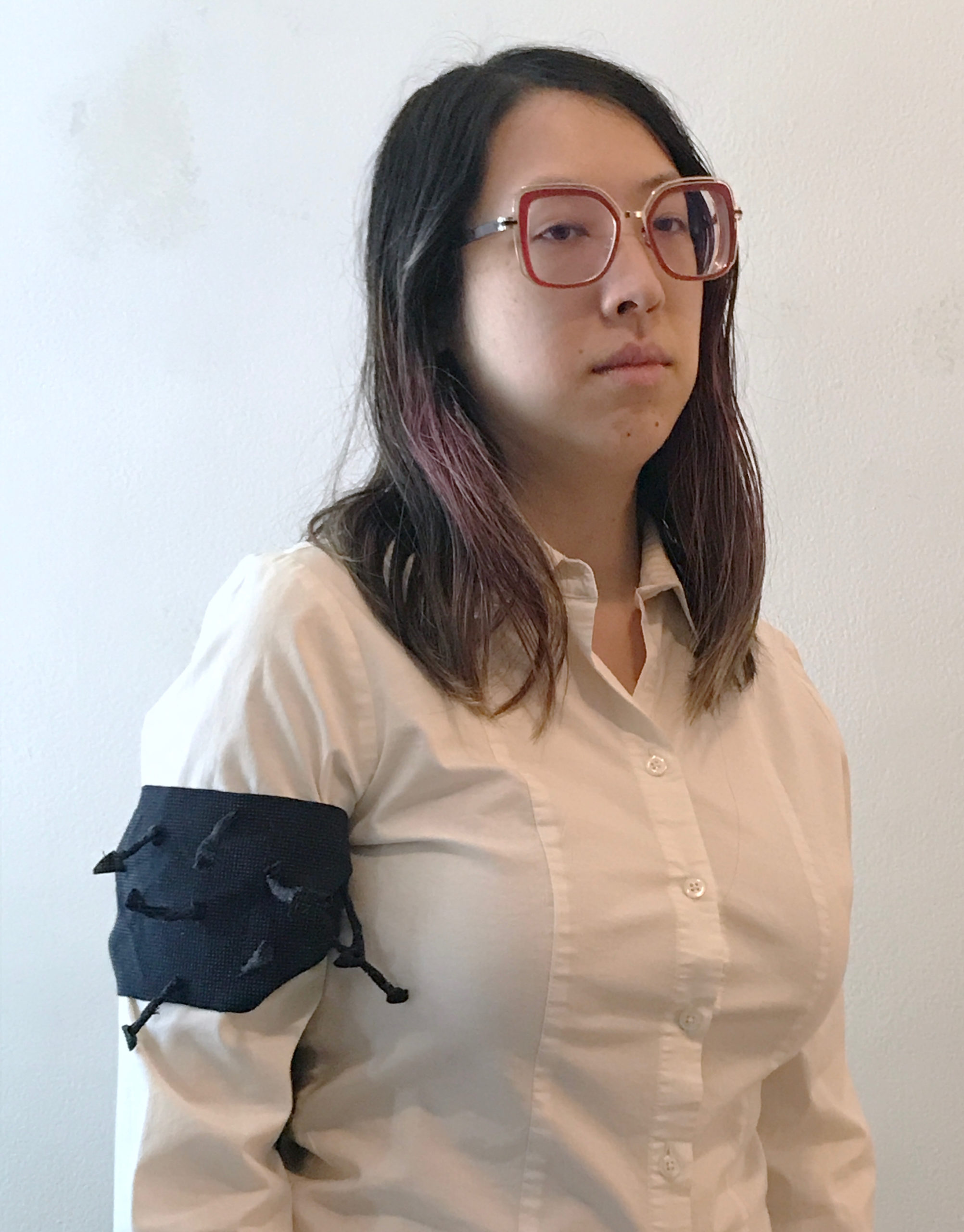 a picture of a woman staring blankly into space, wearing a white shirt with a dark armband that has spikes shooting out of it
