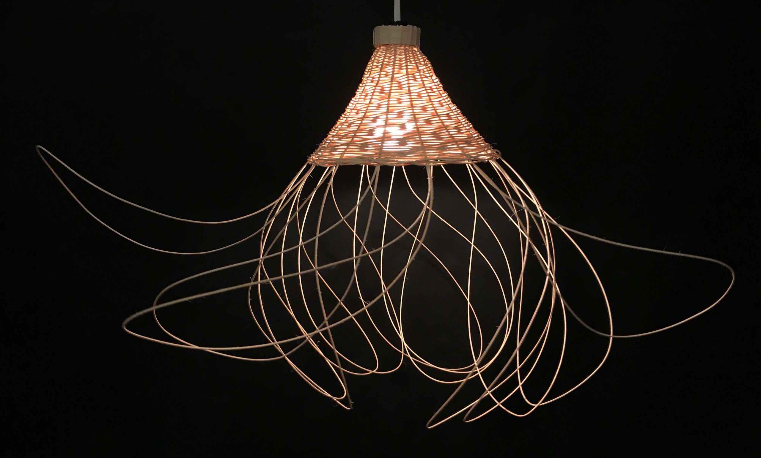 a conical, rattan chandelier with looping fringe sticking out in all directions from the bottom edge of the chandelier