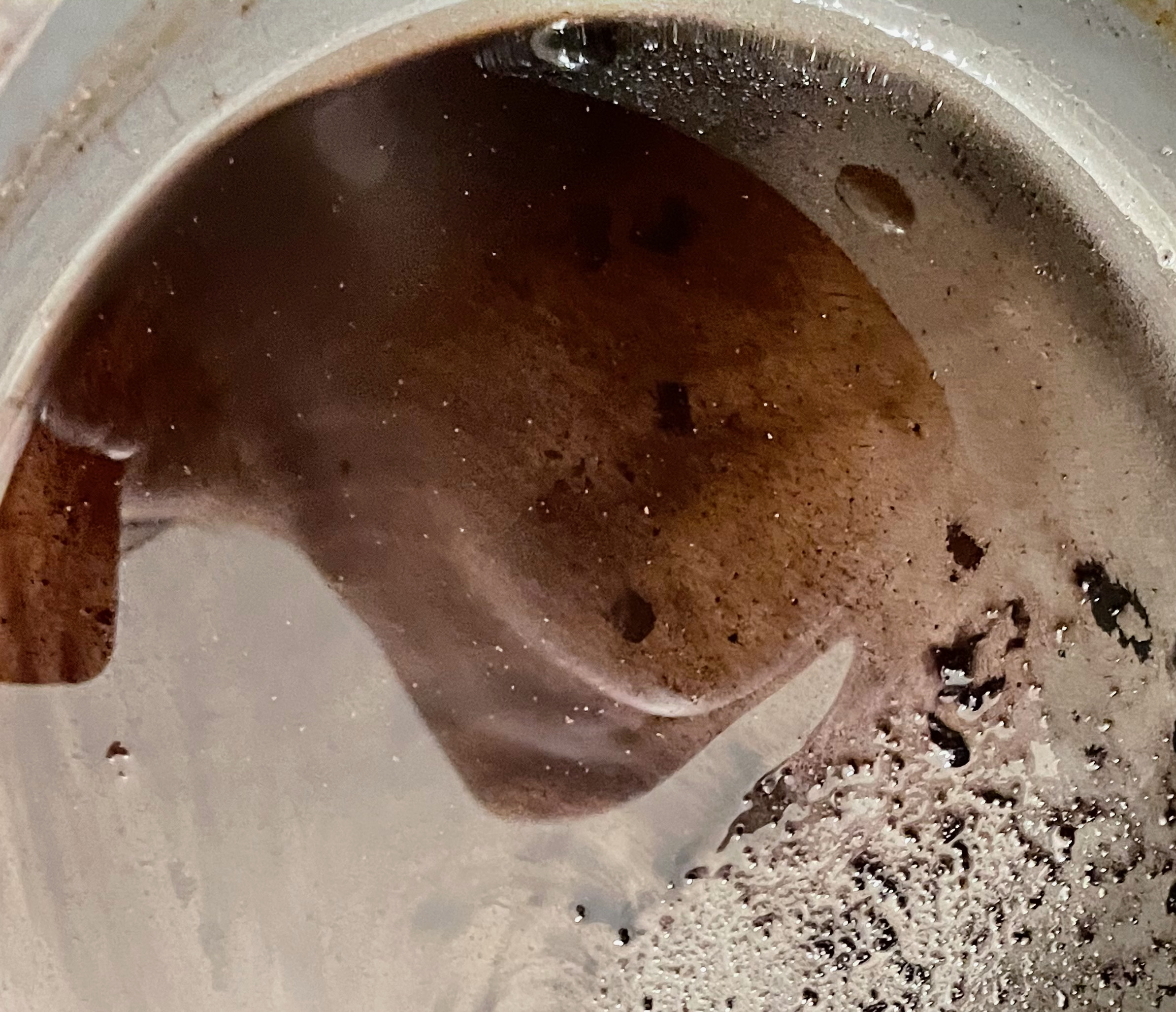 torso reflected in a pot of grease, making the image abstracted so it's difficult to tell what body parts are being depicted