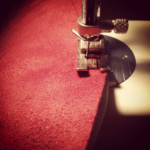 brick red faux suede being sewn on a metal sewing machine