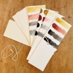 pothi book fanned out, page made from watercolor paper with earth tone color swatches on it
